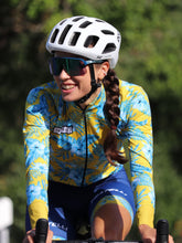 Lade das Bild in den Galerie-Viewer, Frau trägt buntes Rad Langarm Trikot im Hawaii Style mit blau gelber Radhose