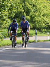 Lade das Bild in den Galerie-Viewer, Frau trägt blau-rosa Langarm Radtrikot und Mann La Nucia buntes Radtrikot und Hawaii Radhose