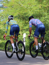 Lade das Bild in den Galerie-Viewer, Frau trägt Cocoa Hawaii Radoutfit mit Langarmtrikot und Mann trägt buntes Marinella Radtrikot und Radhose
